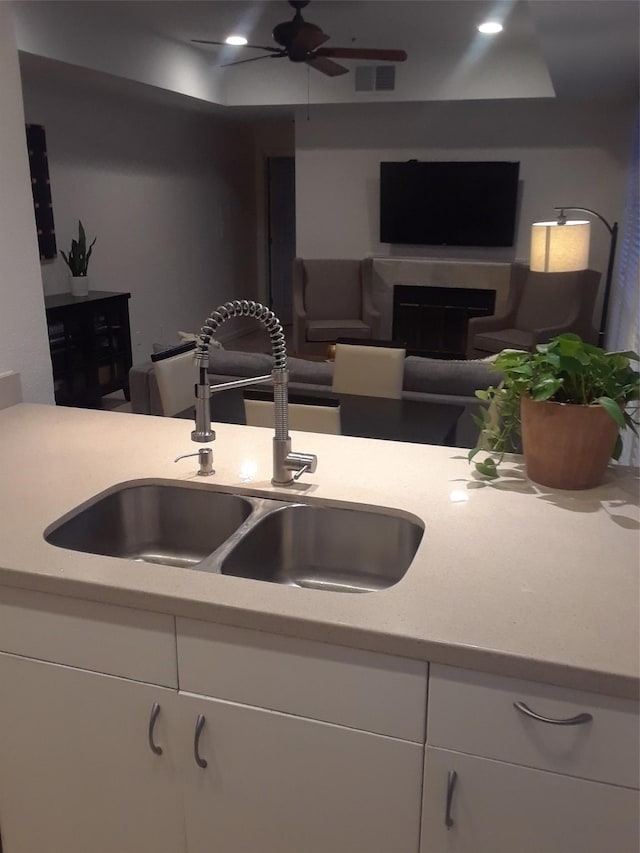 kitchen featuring ceiling fan, white cabinetry, and sink