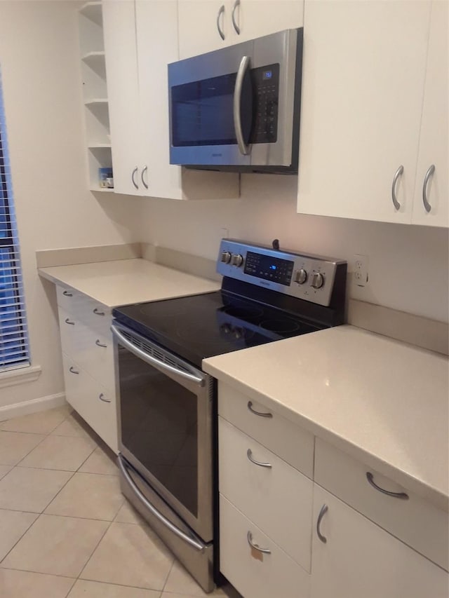 kitchen with white cabinetry, light tile patterned floors, and stainless steel appliances