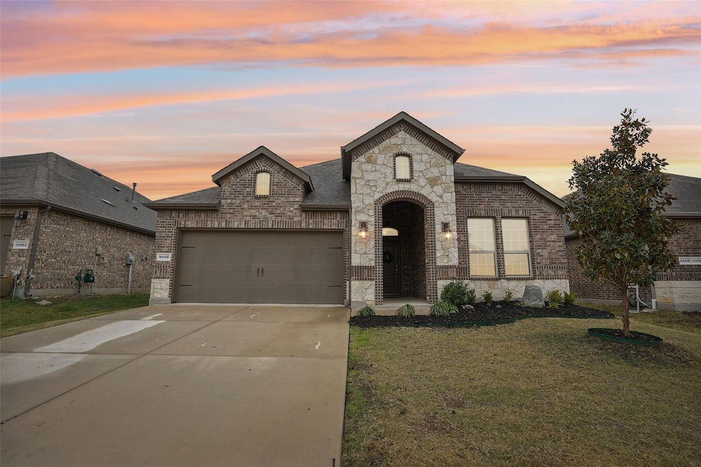 french provincial home with a garage and a lawn