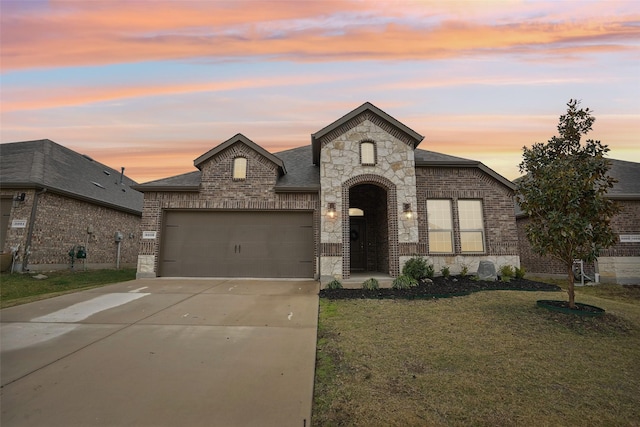 french provincial home with a garage and a lawn