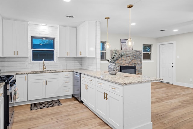 kitchen featuring black gas stove, white cabinetry, sink, and hanging light fixtures