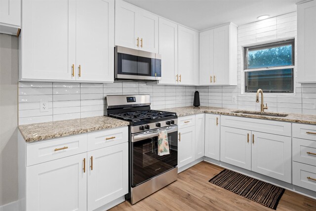 kitchen featuring white cabinets, stainless steel appliances, light hardwood / wood-style flooring, and sink