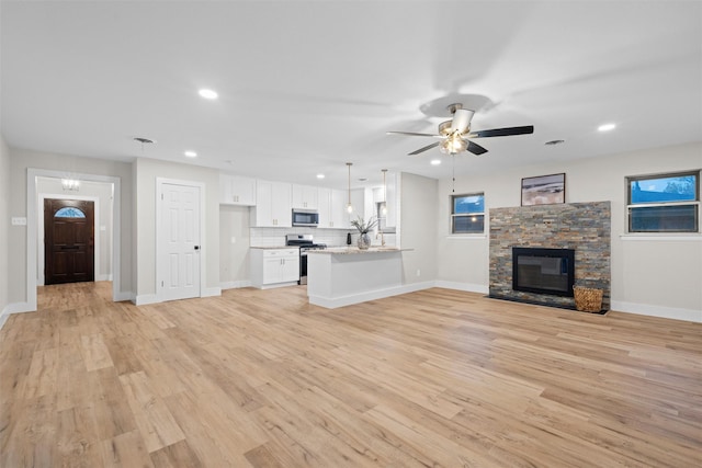 unfurnished living room featuring ceiling fan, a fireplace, and light hardwood / wood-style floors