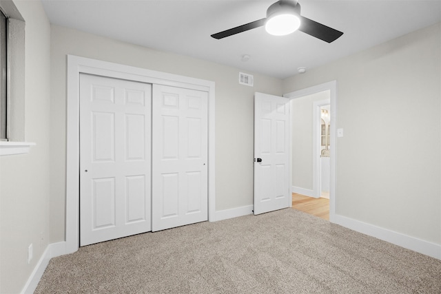 unfurnished bedroom with ceiling fan, a closet, and light carpet