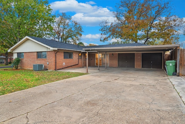 ranch-style home with a front yard, a garage, and central air condition unit