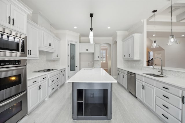 kitchen with arched walkways, stainless steel appliances, a sink, and decorative light fixtures