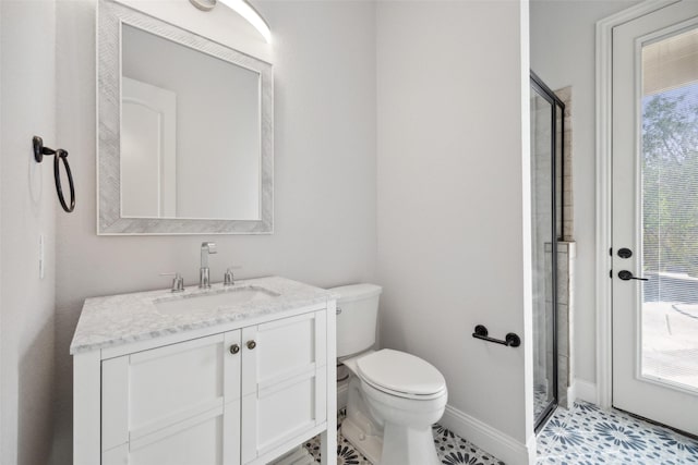 bathroom featuring vanity, a shower stall, toilet, and baseboards