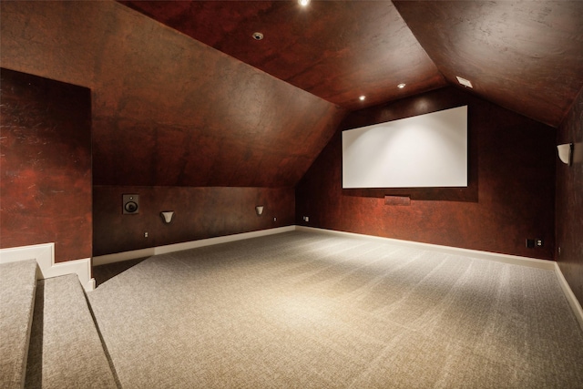 carpeted home theater room featuring baseboards and vaulted ceiling