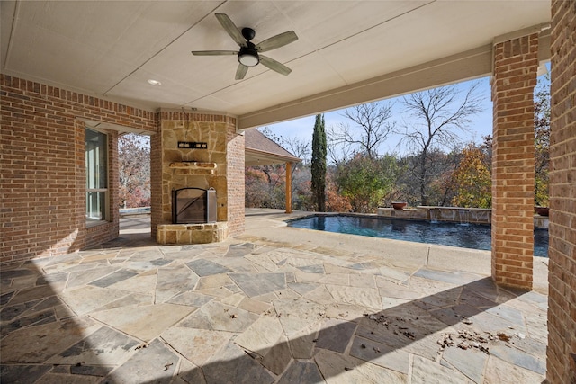 view of patio featuring ceiling fan, an outdoor stone fireplace, and an outdoor pool