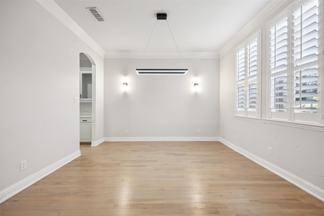 spare room with arched walkways, light wood-type flooring, visible vents, and crown molding