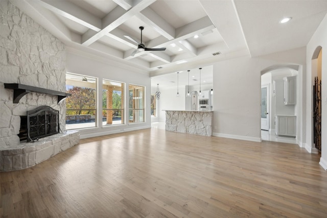 unfurnished living room featuring coffered ceiling, a fireplace, wood finished floors, and a ceiling fan