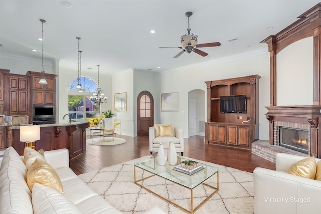 living room featuring a brick fireplace, ornamental molding, and light wood-type flooring