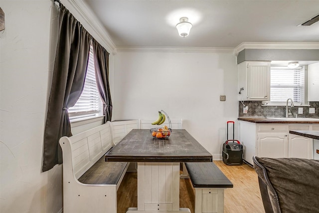 dining area with crown molding, sink, and light hardwood / wood-style flooring