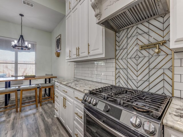 kitchen featuring tasteful backsplash, light stone counters, range hood, black range with gas cooktop, and white cabinets