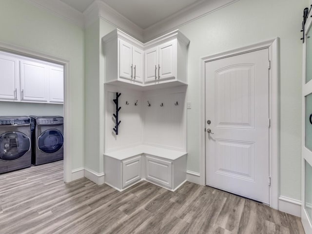 mudroom featuring light wood-type flooring, a barn door, crown molding, and washing machine and clothes dryer