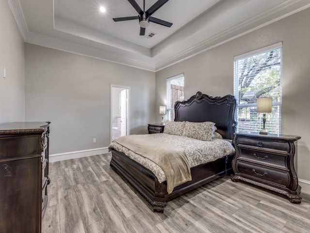 bedroom featuring ensuite bath, ceiling fan, ornamental molding, a tray ceiling, and light hardwood / wood-style floors