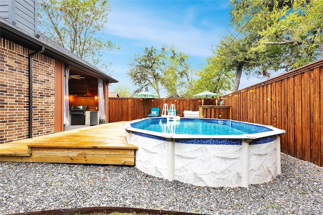 view of swimming pool with a grill and a wooden deck