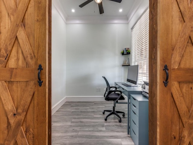 office space featuring a barn door, crown molding, hardwood / wood-style floors, and ceiling fan