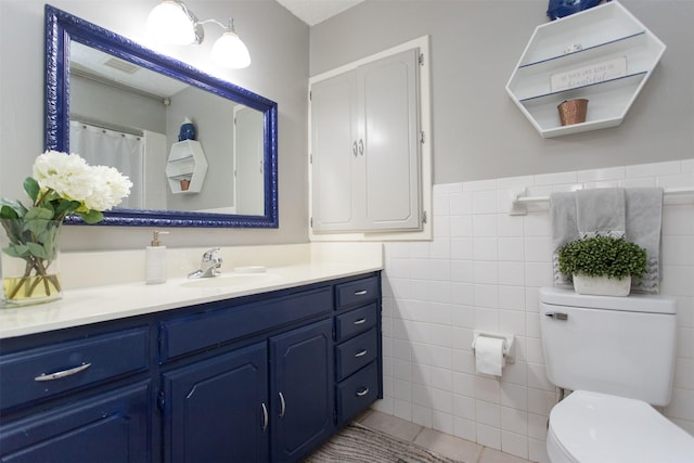 bathroom with tile patterned flooring, vanity, toilet, and tile walls