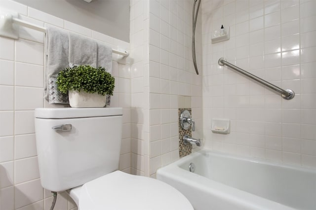 bathroom featuring tiled shower / bath, tile walls, and toilet