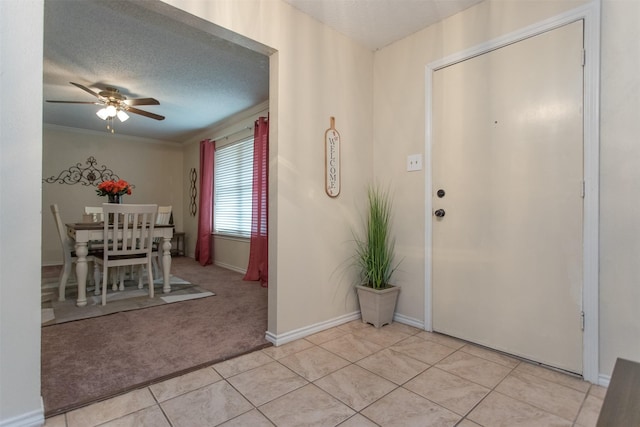 tiled foyer featuring a textured ceiling, ceiling fan, and ornamental molding