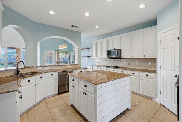 kitchen with a sink, visible vents, appliances with stainless steel finishes, a center island, and tasteful backsplash