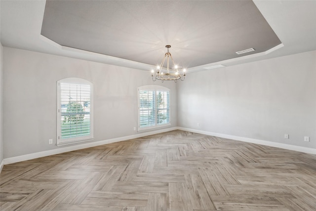 unfurnished room featuring a notable chandelier, a wealth of natural light, and light parquet flooring