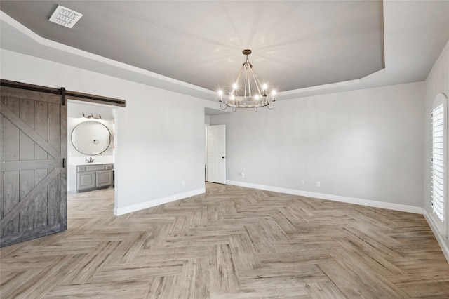 interior space featuring a tray ceiling, light parquet floors, sink, a barn door, and a chandelier