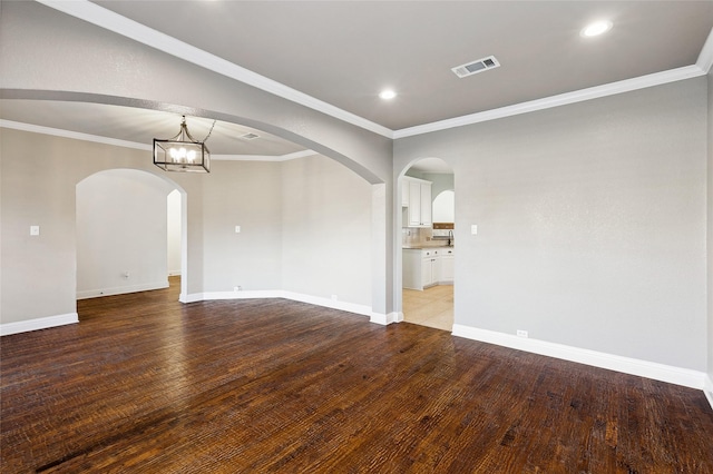 unfurnished room featuring hardwood / wood-style flooring, an inviting chandelier, and ornamental molding