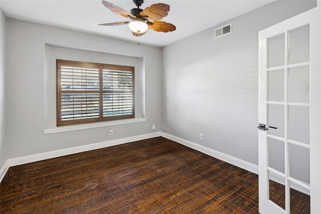 empty room with baseboards, visible vents, dark wood-style flooring, and a ceiling fan