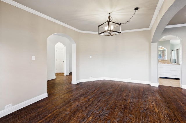 unfurnished dining area with arched walkways, crown molding, wood finished floors, a chandelier, and baseboards