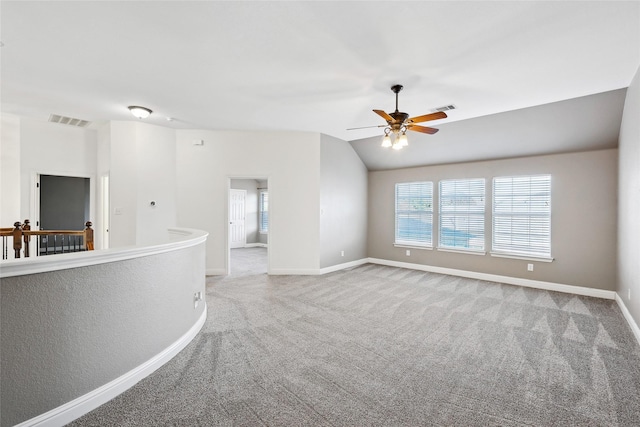 empty room featuring carpet flooring, visible vents, vaulted ceiling, and baseboards