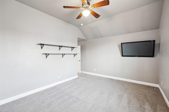 empty room with lofted ceiling, ceiling fan, baseboards, and light colored carpet