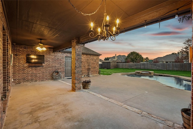 patio terrace at dusk with ceiling fan and a pool with hot tub