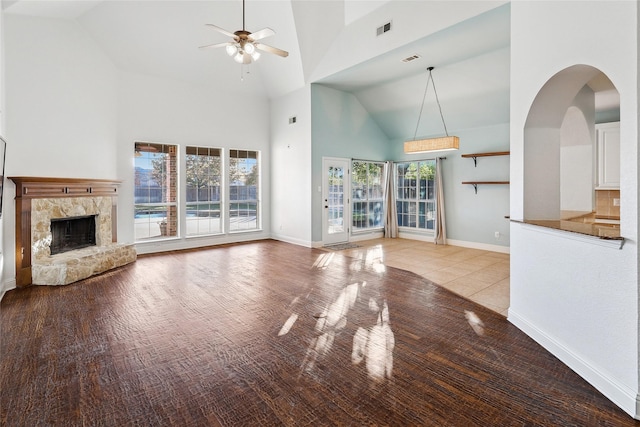 unfurnished living room with a fireplace, high vaulted ceiling, a healthy amount of sunlight, and light hardwood / wood-style floors