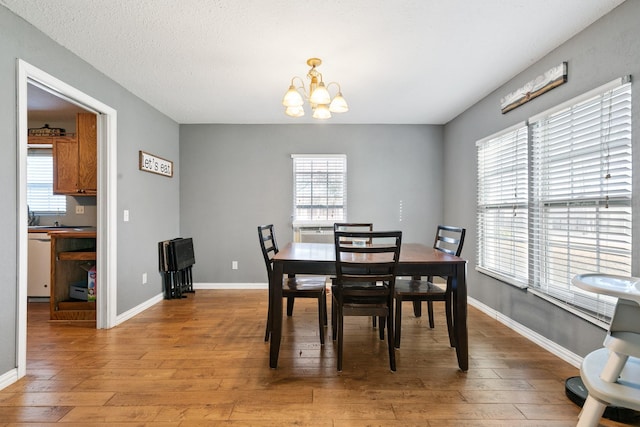 dining space with a textured ceiling, a chandelier, and light wood-type flooring