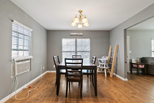 dining room with cooling unit, a notable chandelier, wood-type flooring, and a healthy amount of sunlight