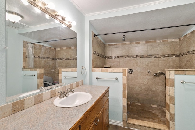 bathroom with vanity, crown molding, and tiled shower