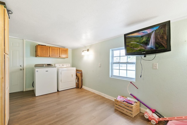 laundry area with crown molding, light hardwood / wood-style flooring, cabinets, washer and dryer, and a textured ceiling