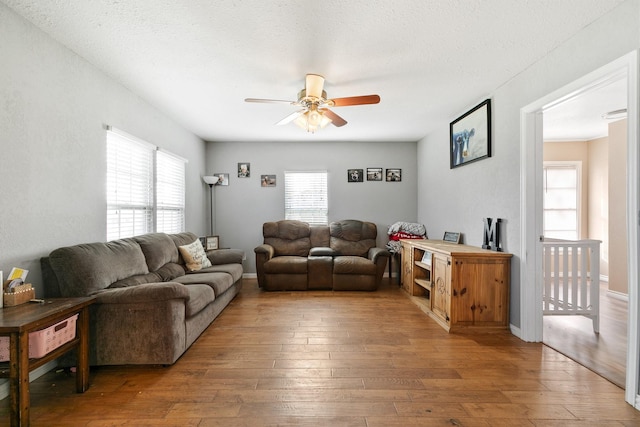 living room featuring ceiling fan, hardwood / wood-style floors, and a textured ceiling