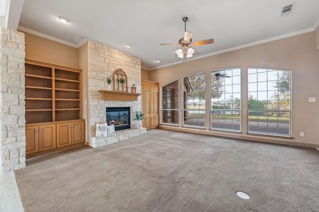 unfurnished living room with a stone fireplace, ornamental molding, light colored carpet, and ceiling fan