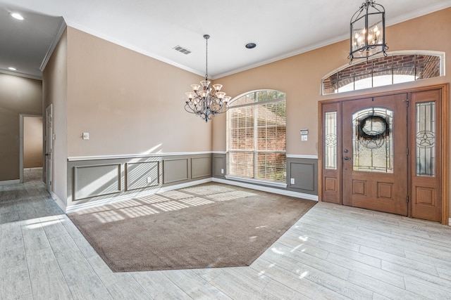 foyer with ornamental molding, light hardwood / wood-style floors, and a notable chandelier