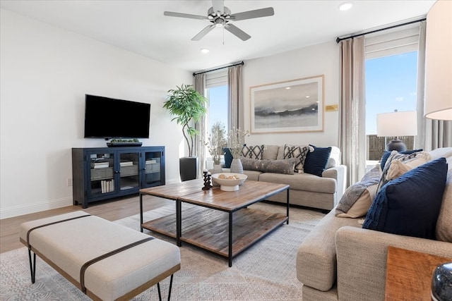 living room with light hardwood / wood-style flooring, ceiling fan, and a healthy amount of sunlight