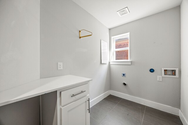 laundry room featuring electric dryer hookup, cabinets, dark tile patterned floors, and washer hookup