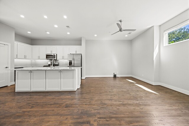 kitchen featuring appliances with stainless steel finishes, dark hardwood / wood-style flooring, ceiling fan, white cabinets, and an island with sink