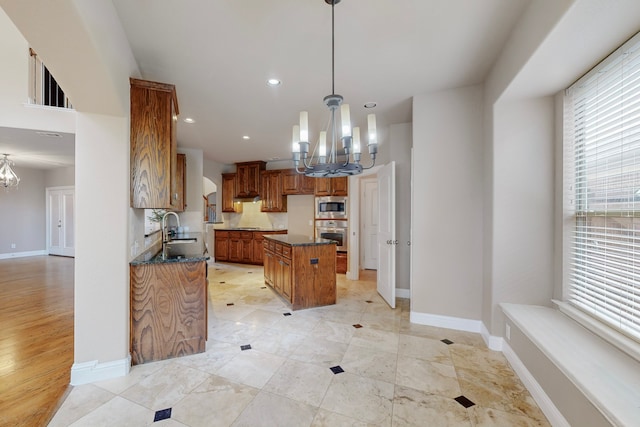 kitchen featuring appliances with stainless steel finishes, sink, pendant lighting, an inviting chandelier, and a center island