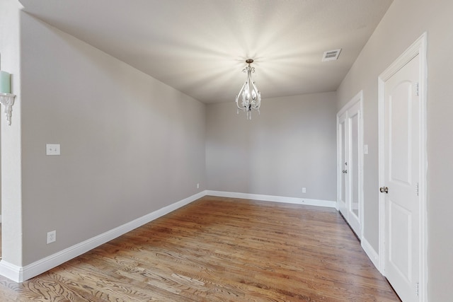 spare room with light hardwood / wood-style flooring and a chandelier