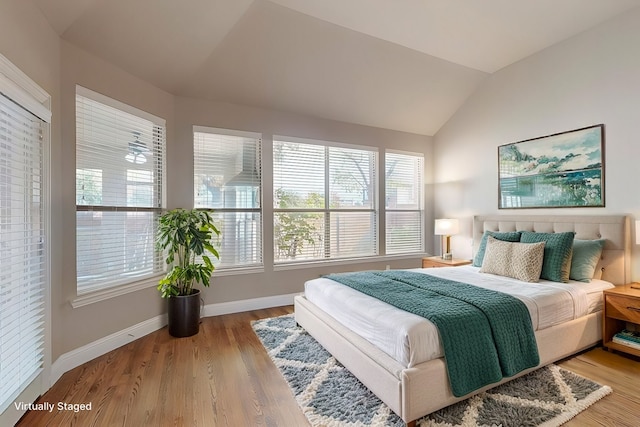 bedroom with baseboards, vaulted ceiling, and wood finished floors