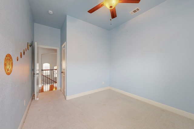 empty room featuring ceiling fan, carpet floors, visible vents, and baseboards