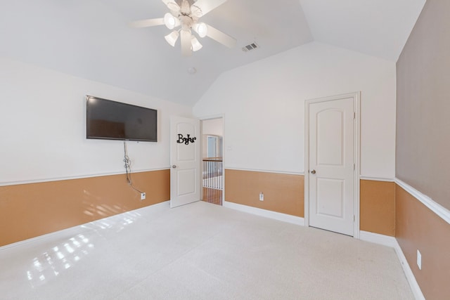 unfurnished bedroom featuring visible vents, baseboards, light colored carpet, ceiling fan, and vaulted ceiling